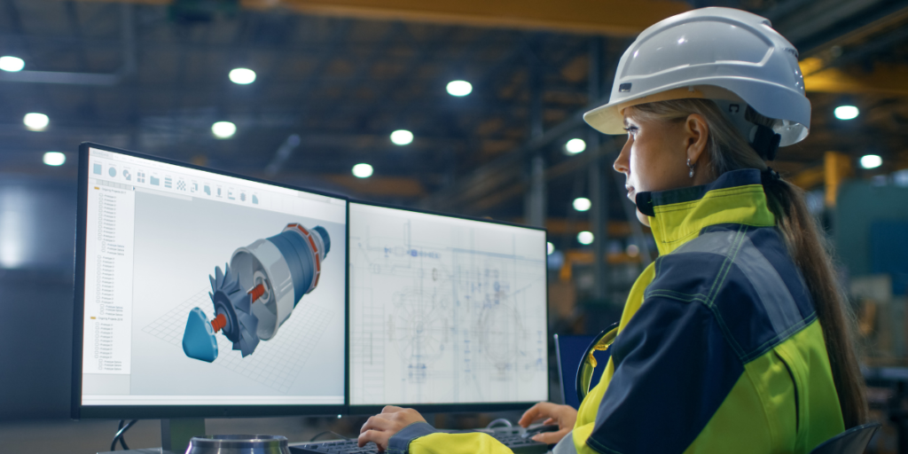 Engineer in safety gear using one of the types of CAD on a computer.