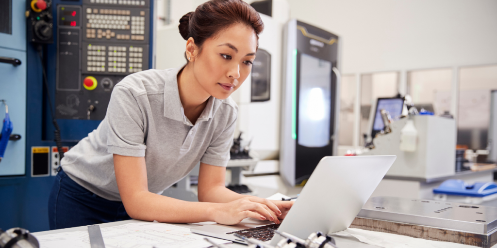 Engineer using CAD software on her laptop on the shop floor.