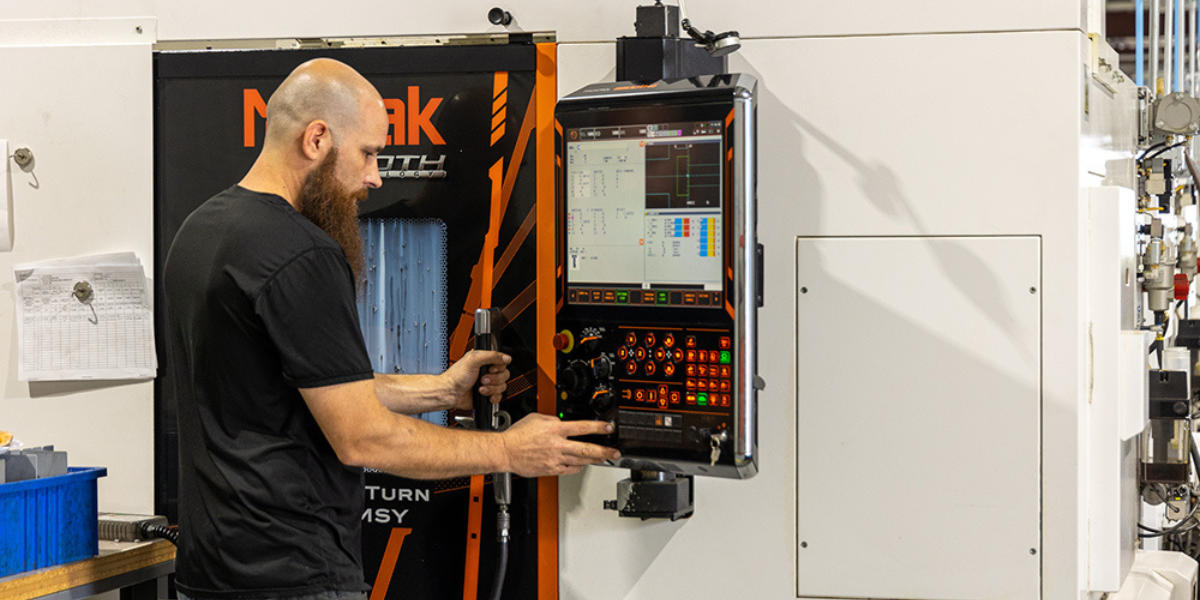 Man operating turning machine using control panel