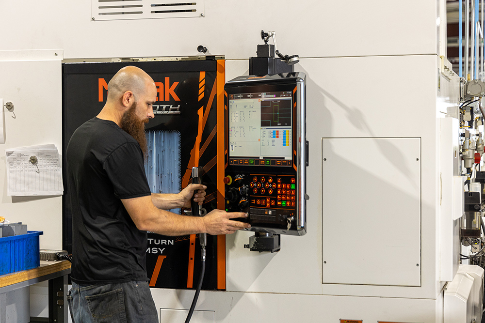 Man operating turning machine using control panel