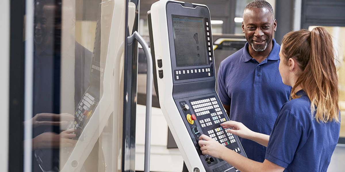 Engineer Showing Apprentice How To Use CNC Tool Making Machine