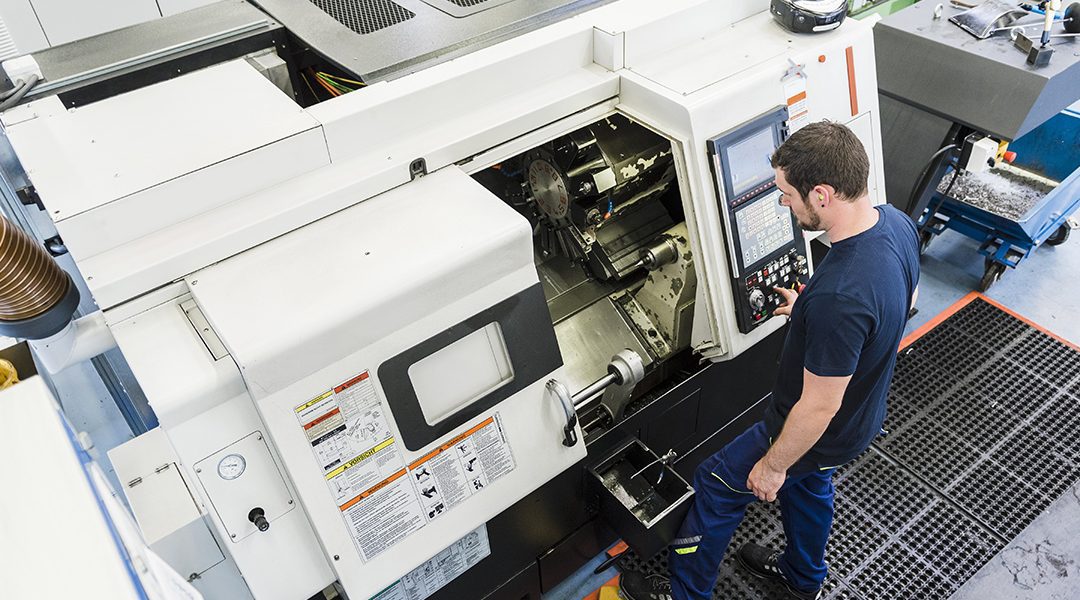 Man operating CNC machine in industrial factory