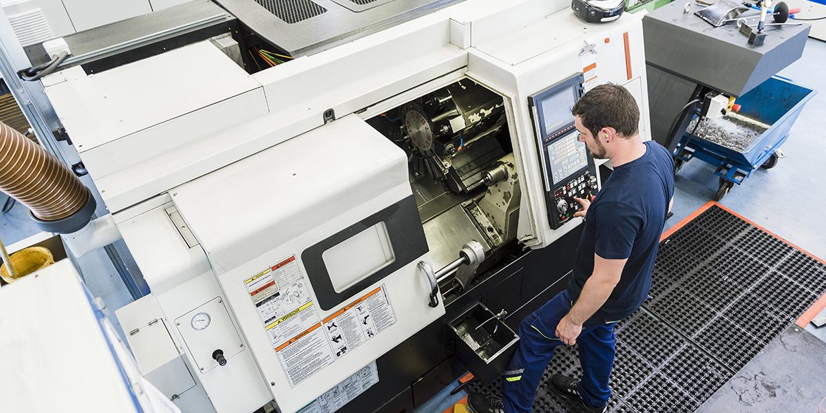 Man operating CNC machine in industrial factory
